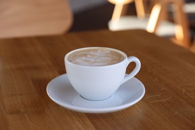 Photo of Cup of aromatic coffee on wooden table in cafe, closeup