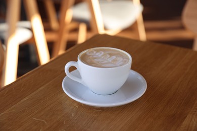 Photo of Cup of aromatic coffee on wooden table in cafe