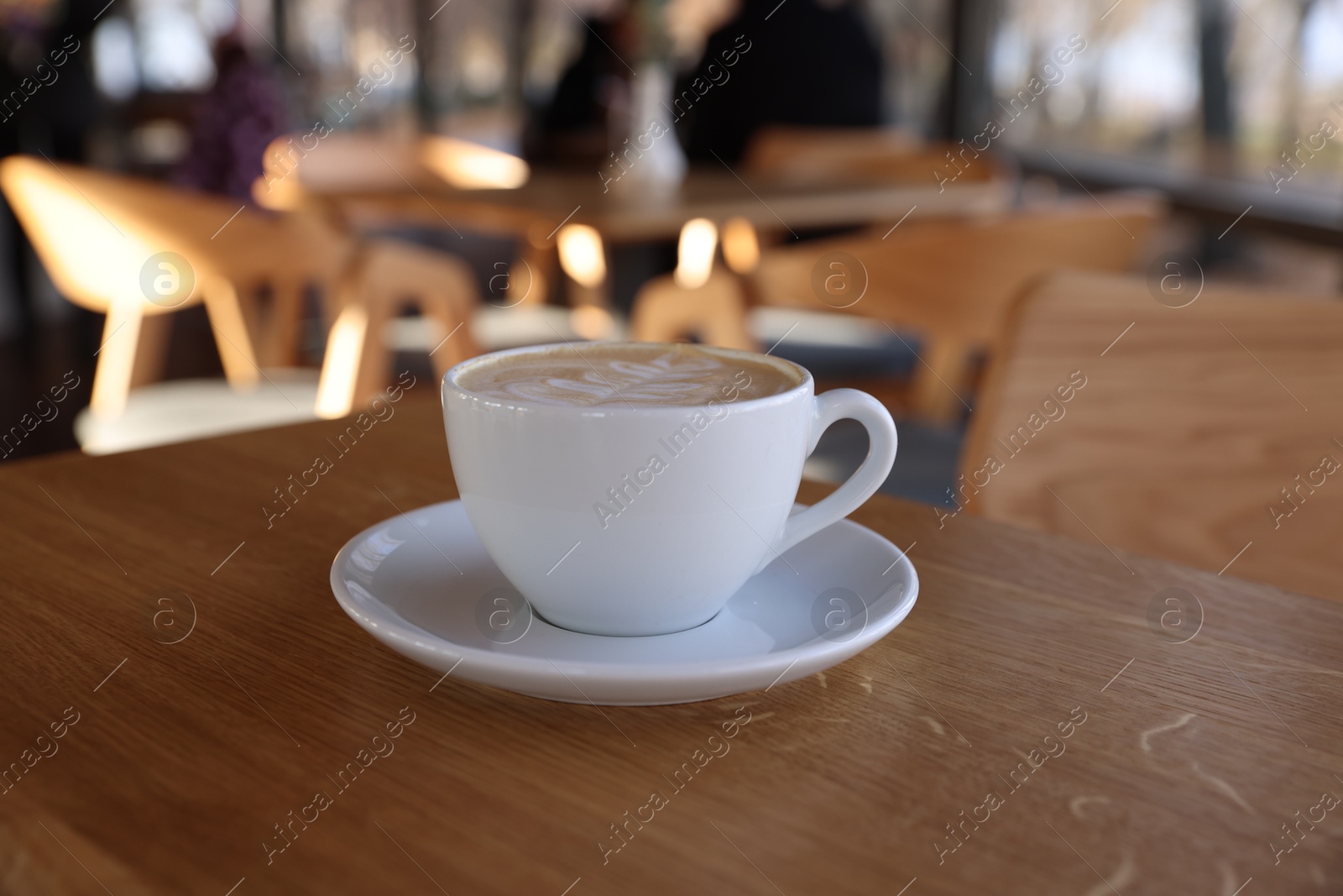 Photo of Cup of aromatic coffee on wooden table in cafe