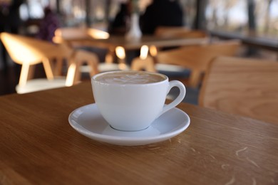 Photo of Cup of aromatic coffee on wooden table in cafe