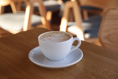 Photo of Cup of aromatic coffee on wooden table in cafe, closeup