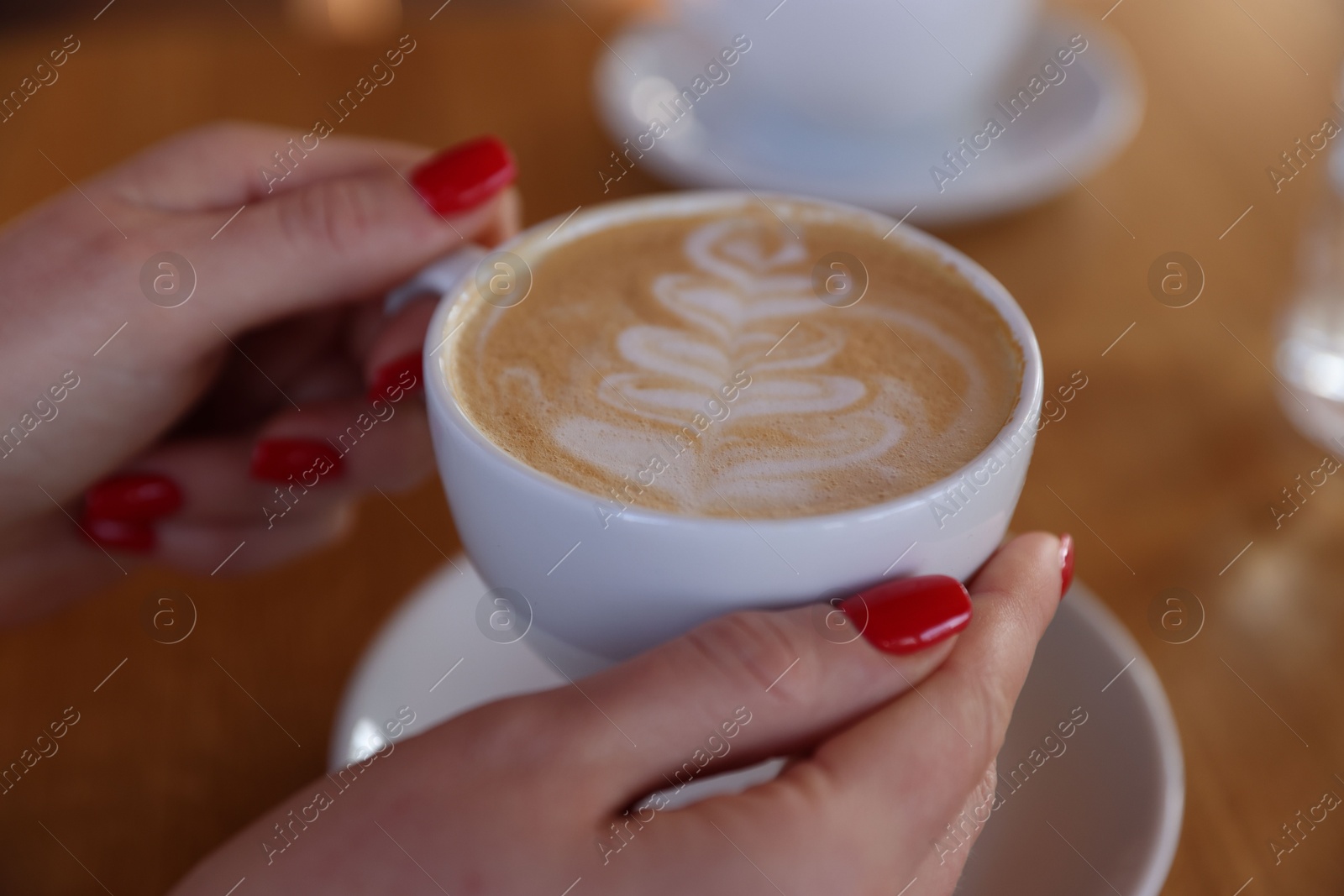 Photo of Woman with cup of aromatic coffee at table in cafe, closeup