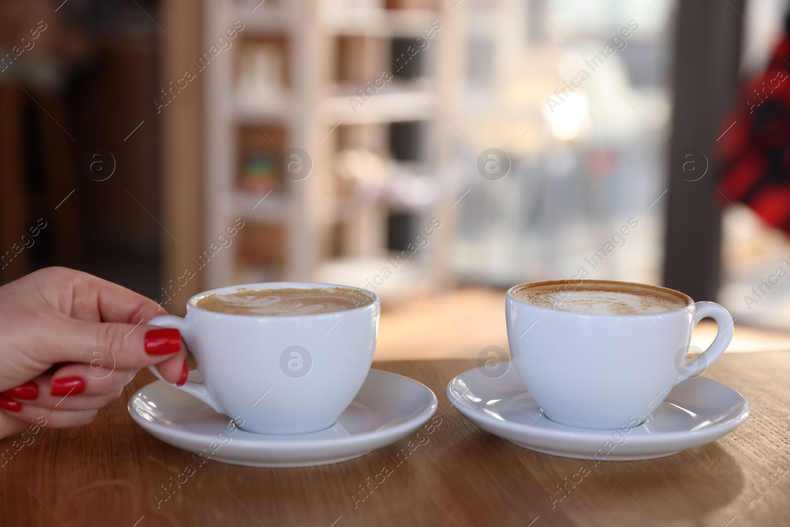 Photo of Woman having coffee break at wooden table with two cups in cafe, closeup