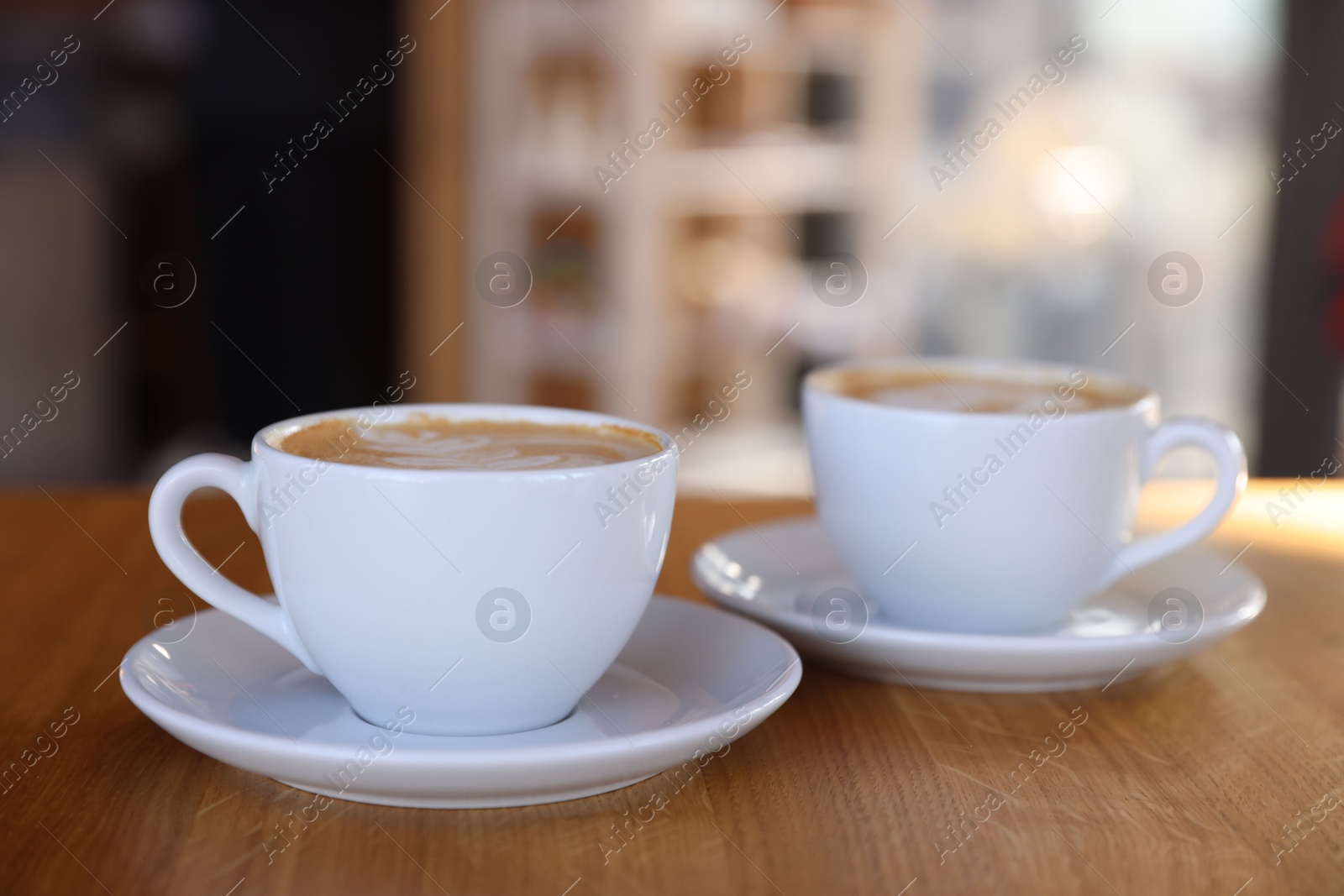 Photo of Cups of aromatic coffee on wooden table in cafe, closeup