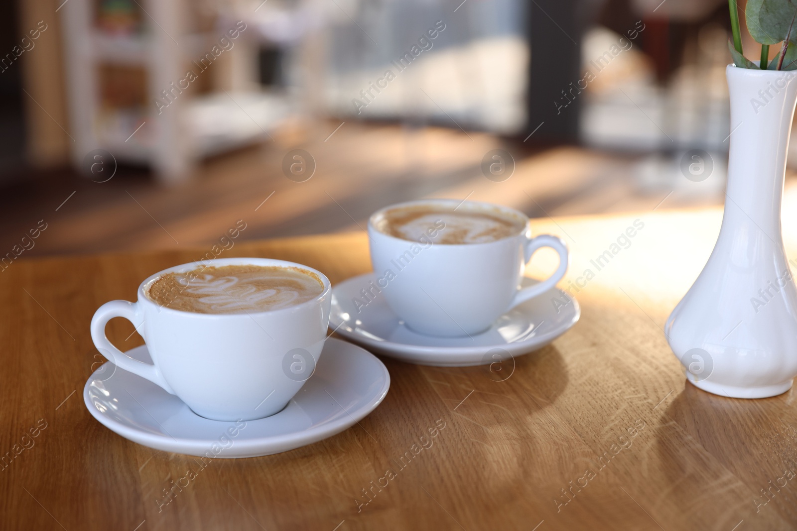 Photo of Cups of aromatic coffee on wooden table in cafe, closeup