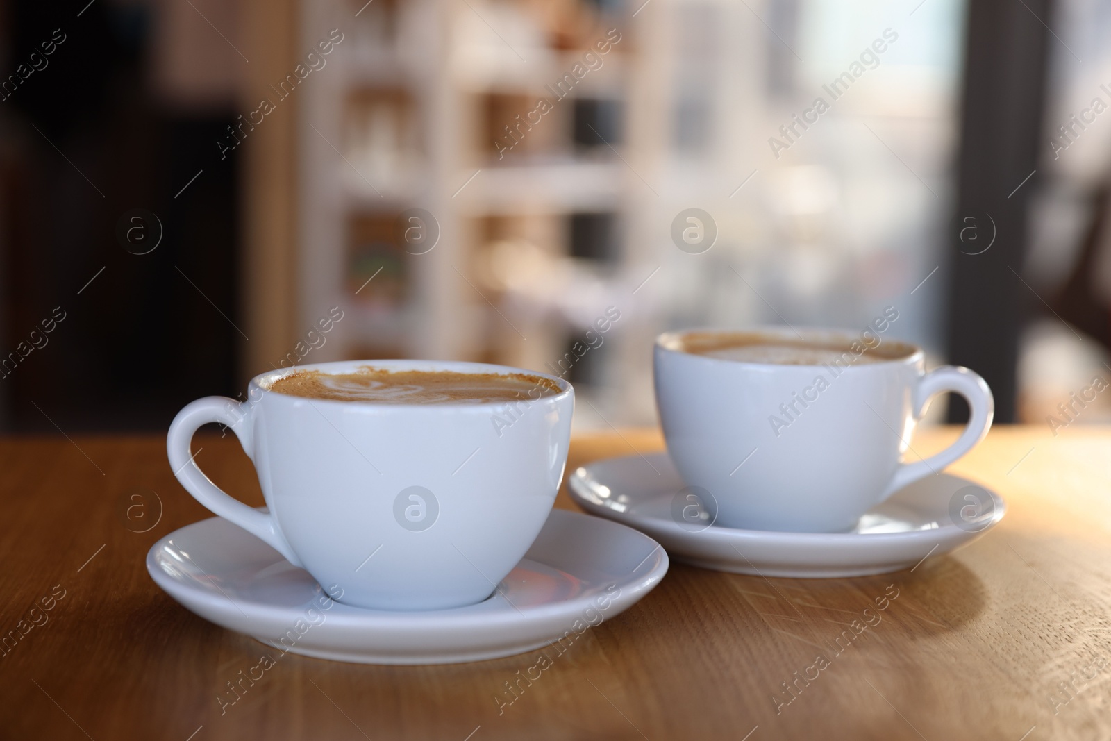 Photo of Cups of aromatic coffee on wooden table in cafe, closeup