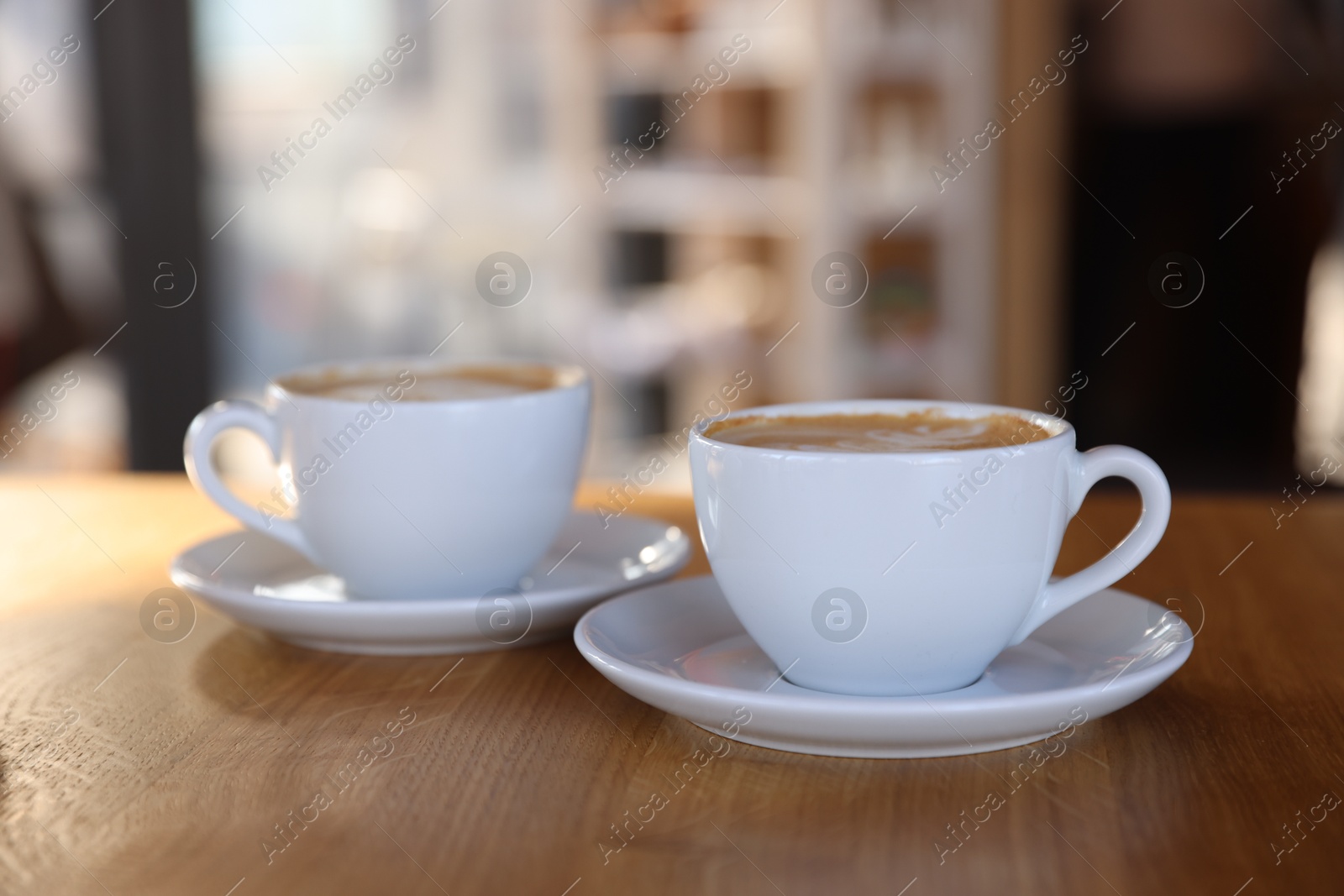 Photo of Cups of aromatic coffee on wooden table in cafe, closeup