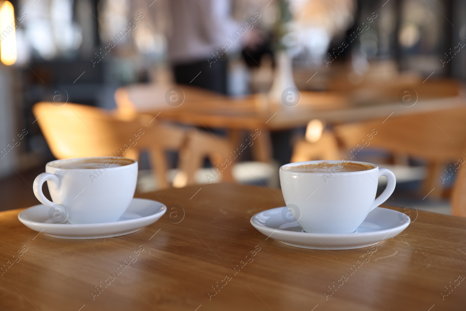 Photo of Cups of aromatic coffee on wooden table in cafe