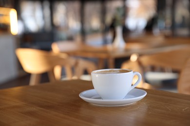 Photo of Cup of aromatic coffee on wooden table in cafe, closeup. Space for text