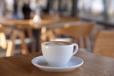 Photo of Cup of aromatic coffee on wooden table in cafe, closeup. Space for text