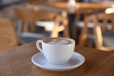 Photo of Cup of aromatic coffee on wooden table in cafe, closeup. Space for text