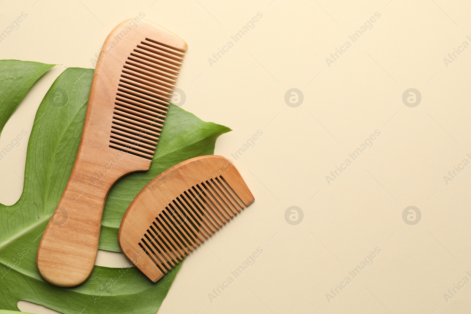 Photo of Wooden hair combs and monstera leaf on beige background, flat lay. Space for text