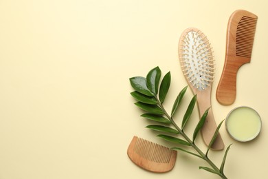 Photo of Wooden hair brush, combs, wax and green branch on beige background, flat lay. Space for text