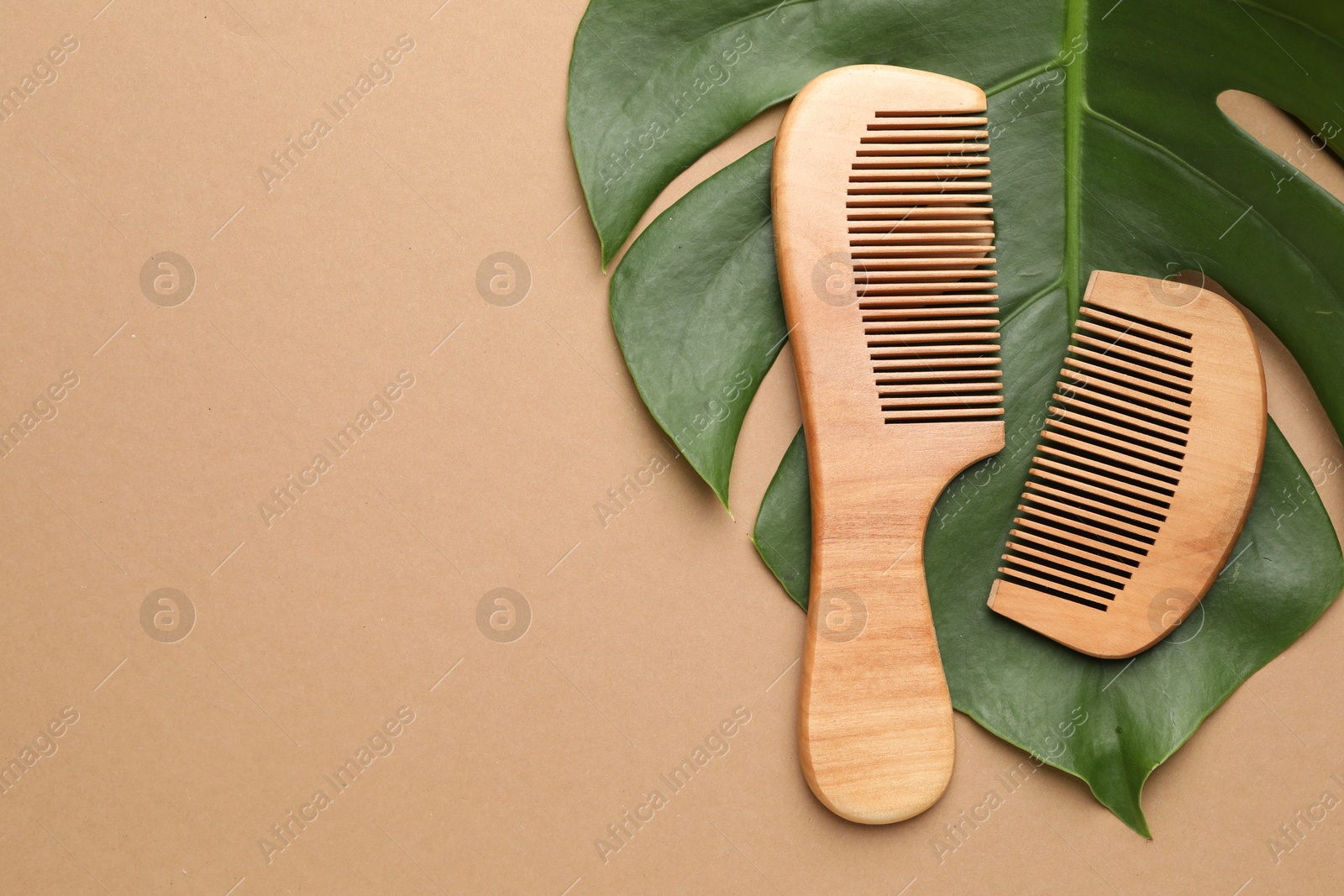 Photo of Wooden hair combs and monstera leaf on dark beige background, flat lay. Space for text