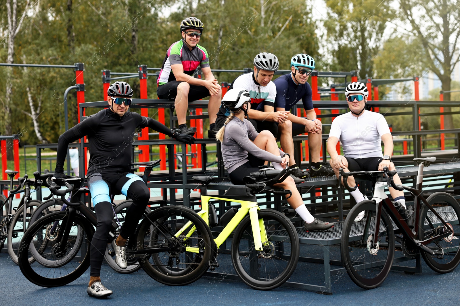 Photo of Group of athletic people with helmets and bicycles spending time together outdoors