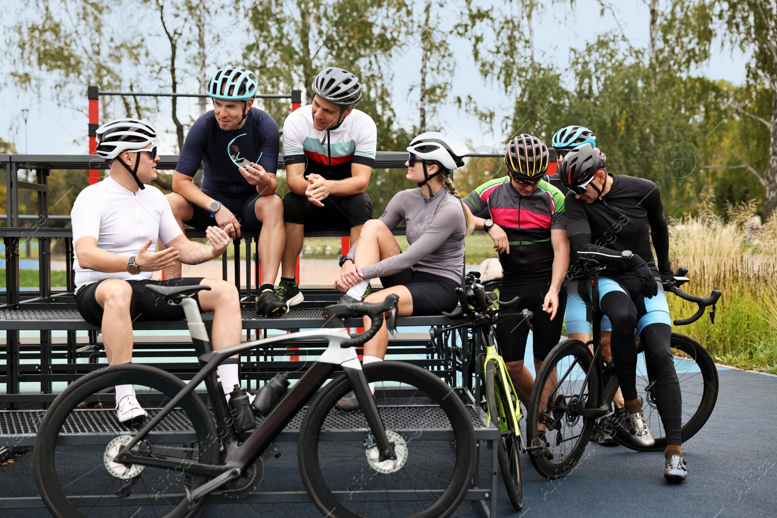 Photo of Group of athletic people with helmets and bicycles spending time together outdoors