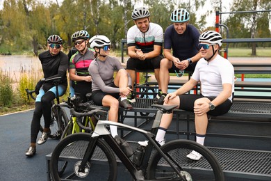 Photo of Group of athletic people with helmets and bicycles spending time together outdoors