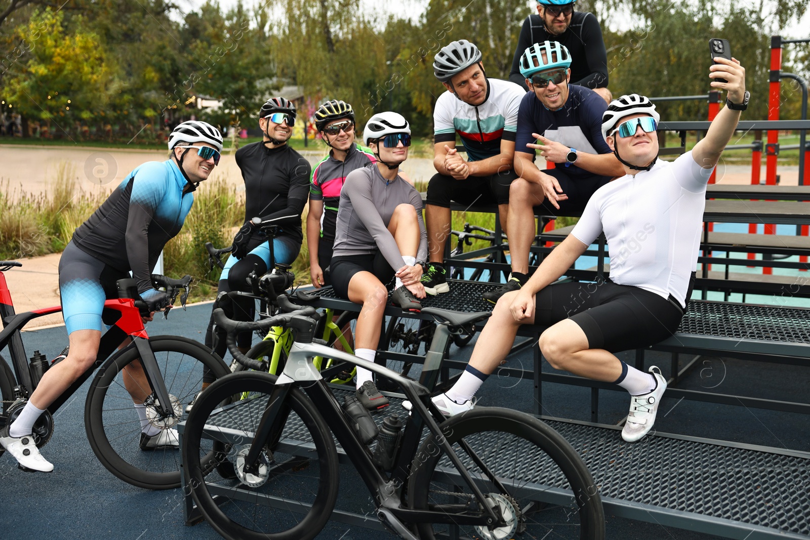 Photo of Group of athletic people with helmets and bicycles taking selfie outdoors