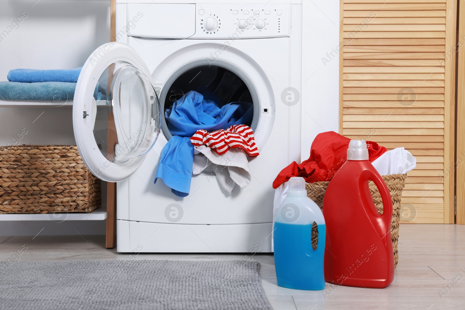 Photo of Washing machine, detergents and basket with laundry in room