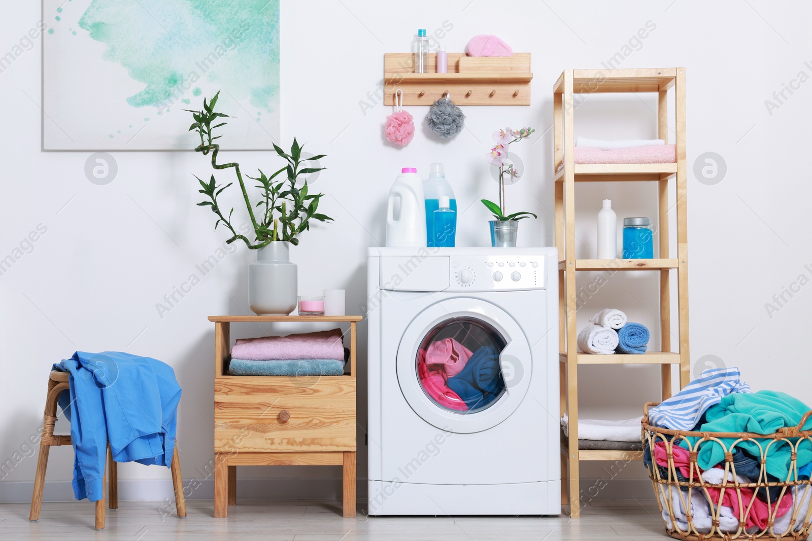 Photo of Washing machine, detergents, clean towels and basket with laundry in room