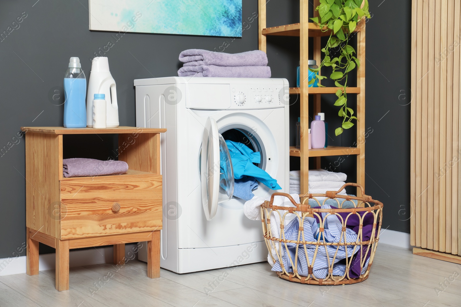 Photo of Washing machine, detergents and basket with laundry in room