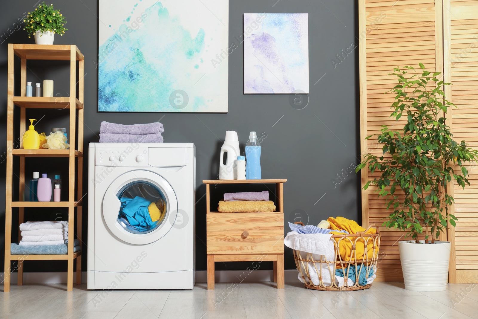 Photo of Washing machine, detergents and basket with laundry in room