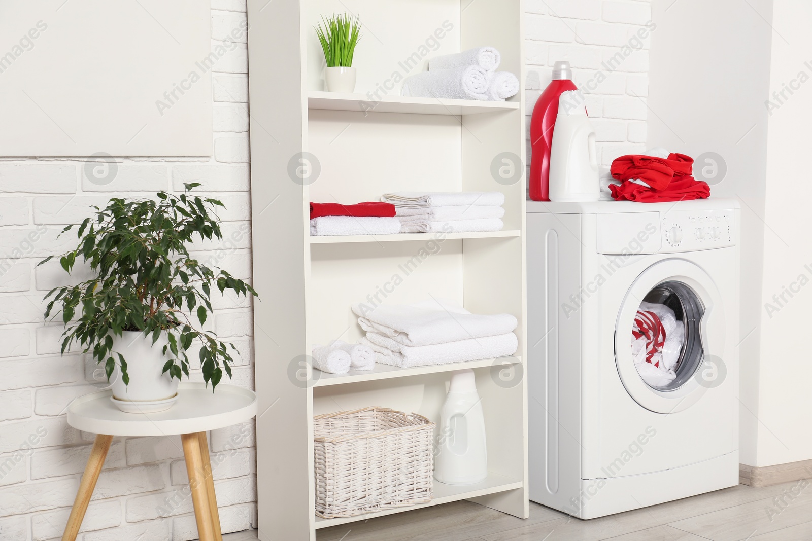 Photo of Washing machine, detergents and towels in room