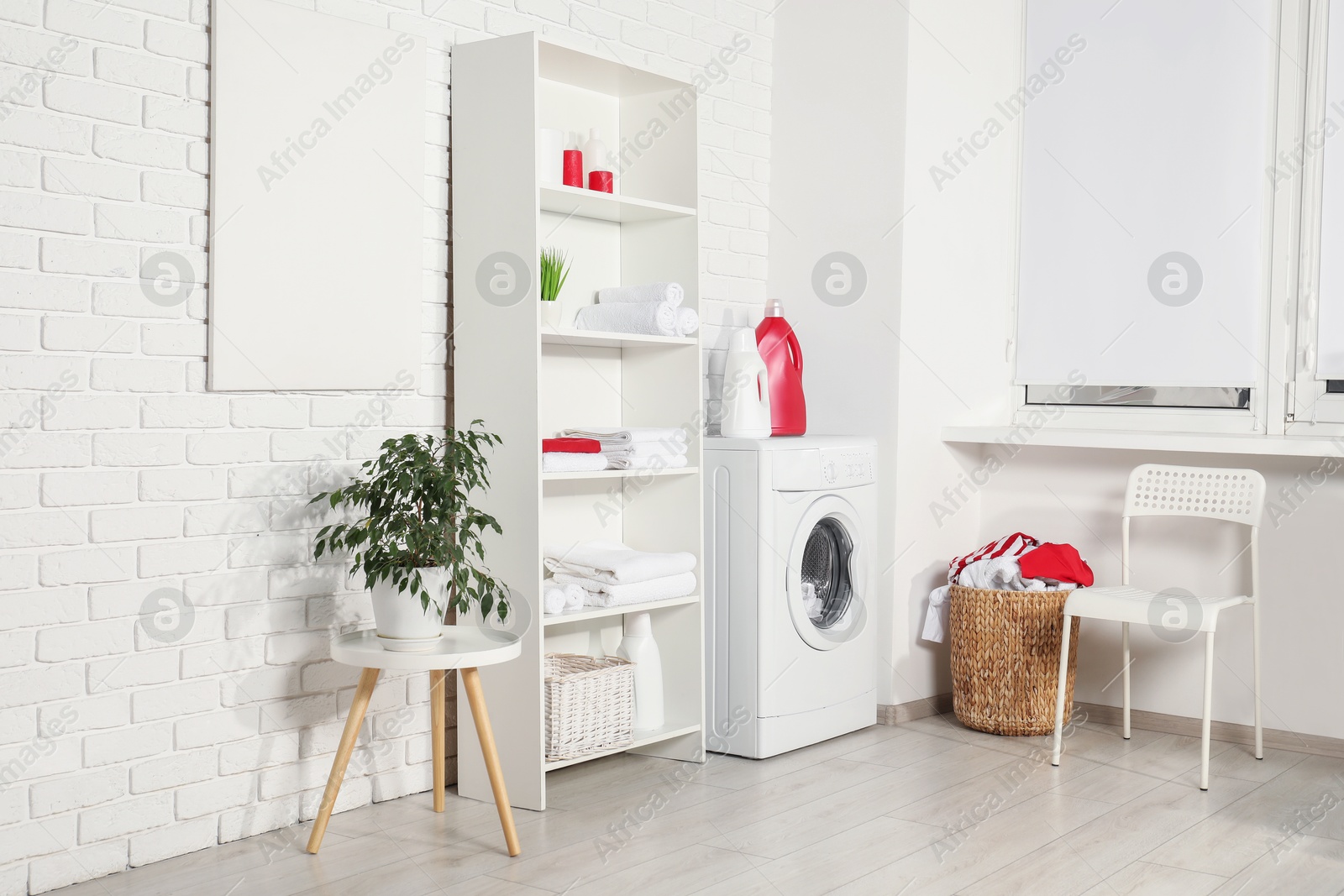 Photo of Washing machine, detergents and basket with laundry in room