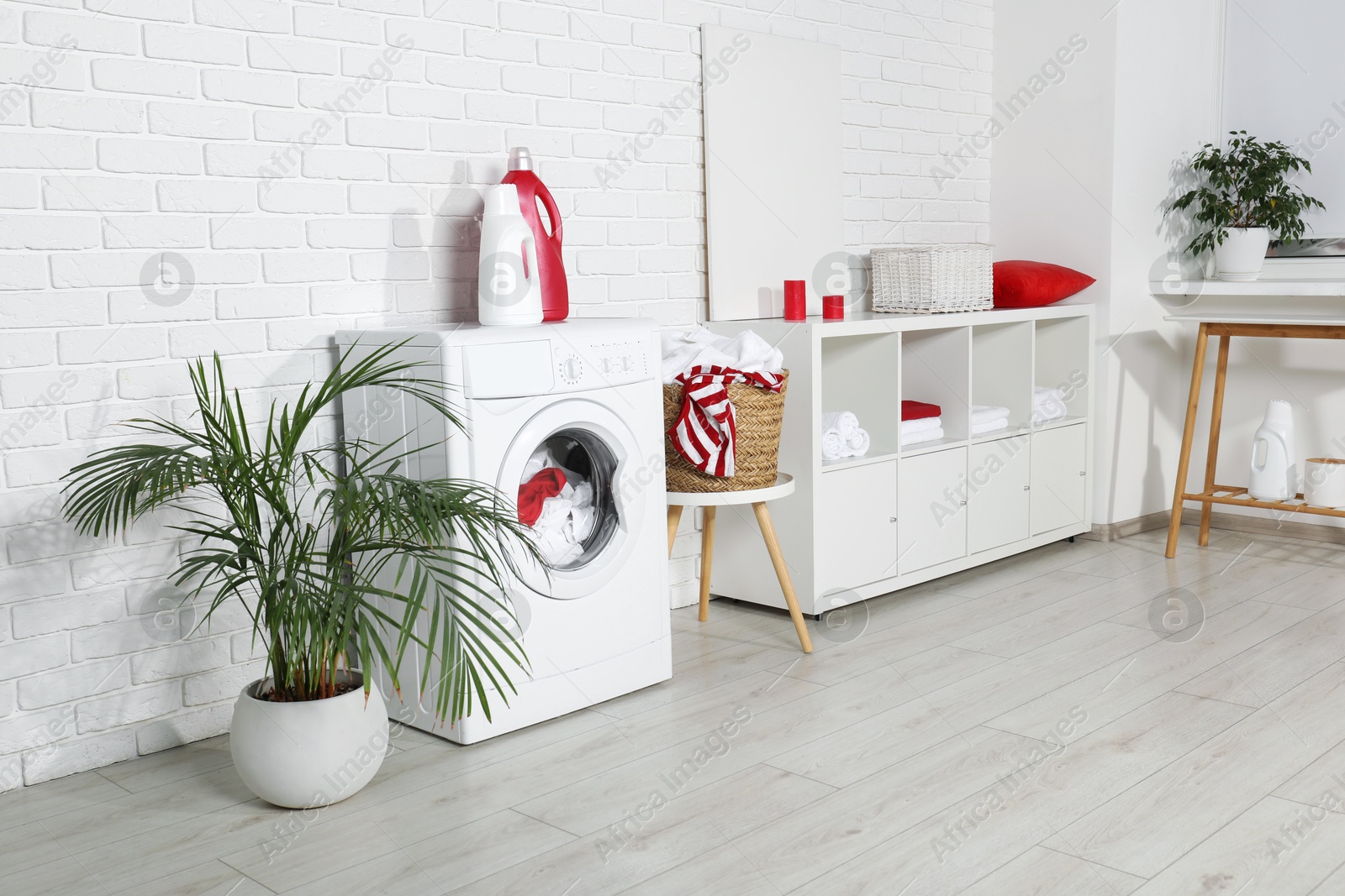 Photo of Washing machine, detergents and basket with laundry in room