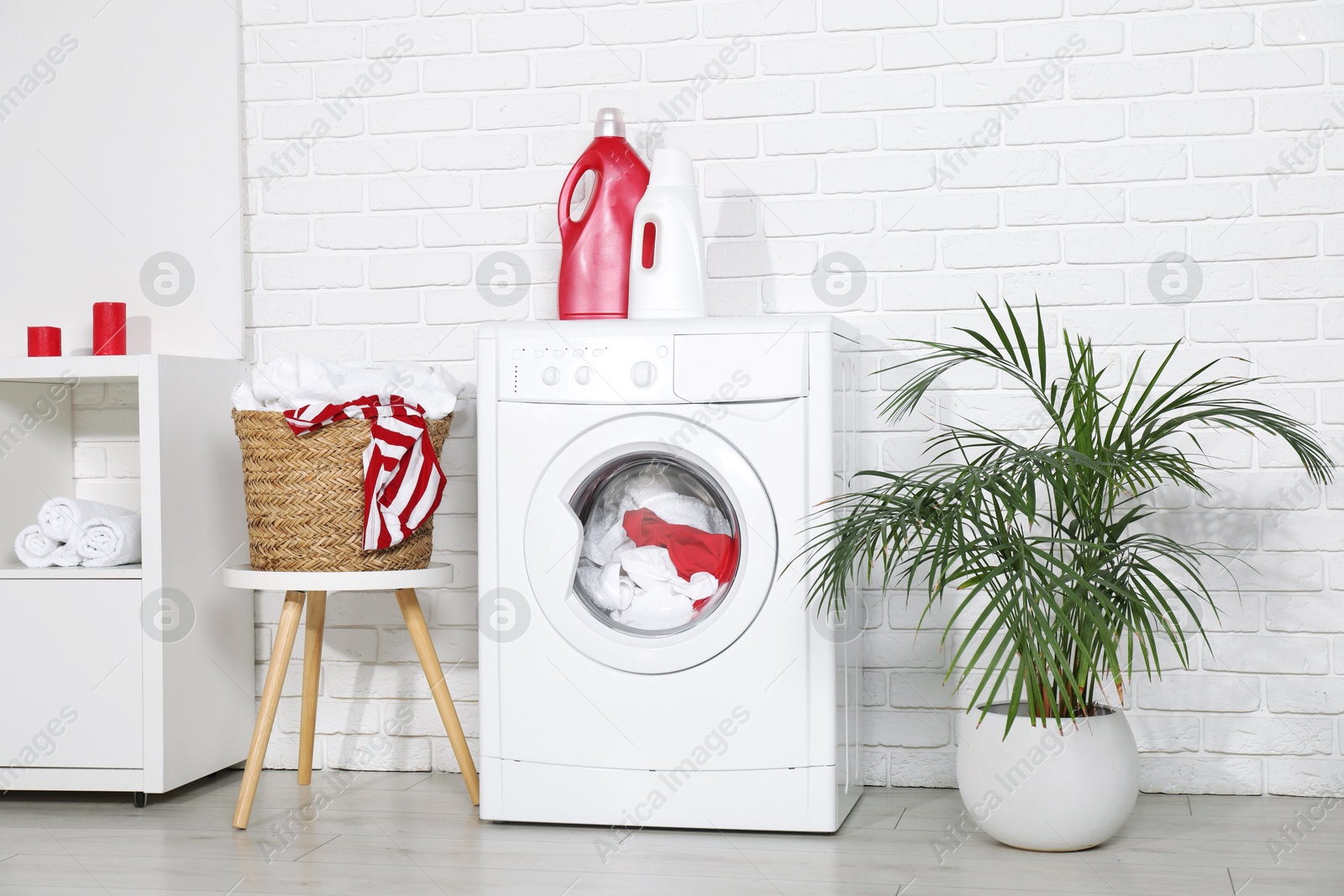 Photo of Washing machine, detergents and basket with laundry in room