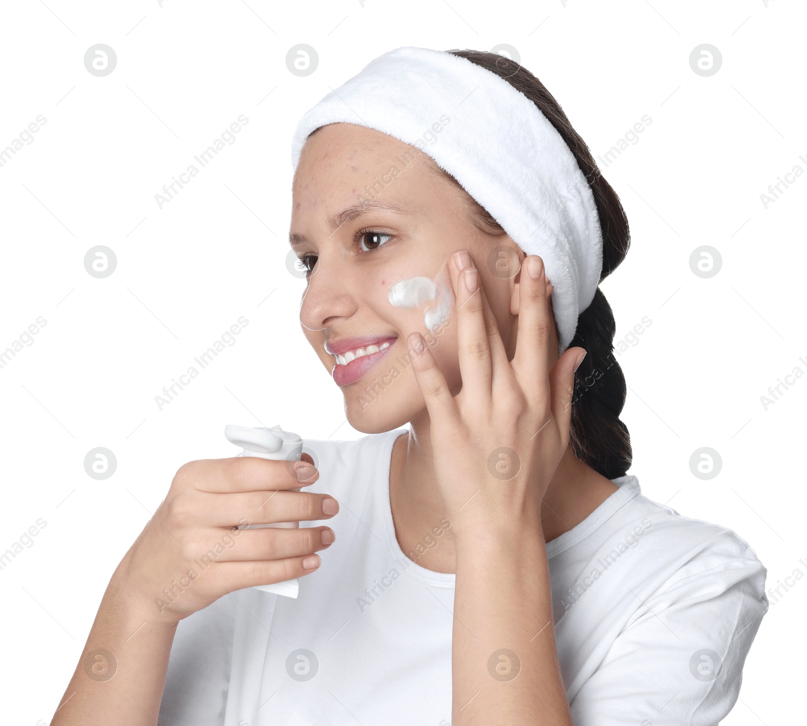 Photo of Teenage girl with acne problem applying cream on white background