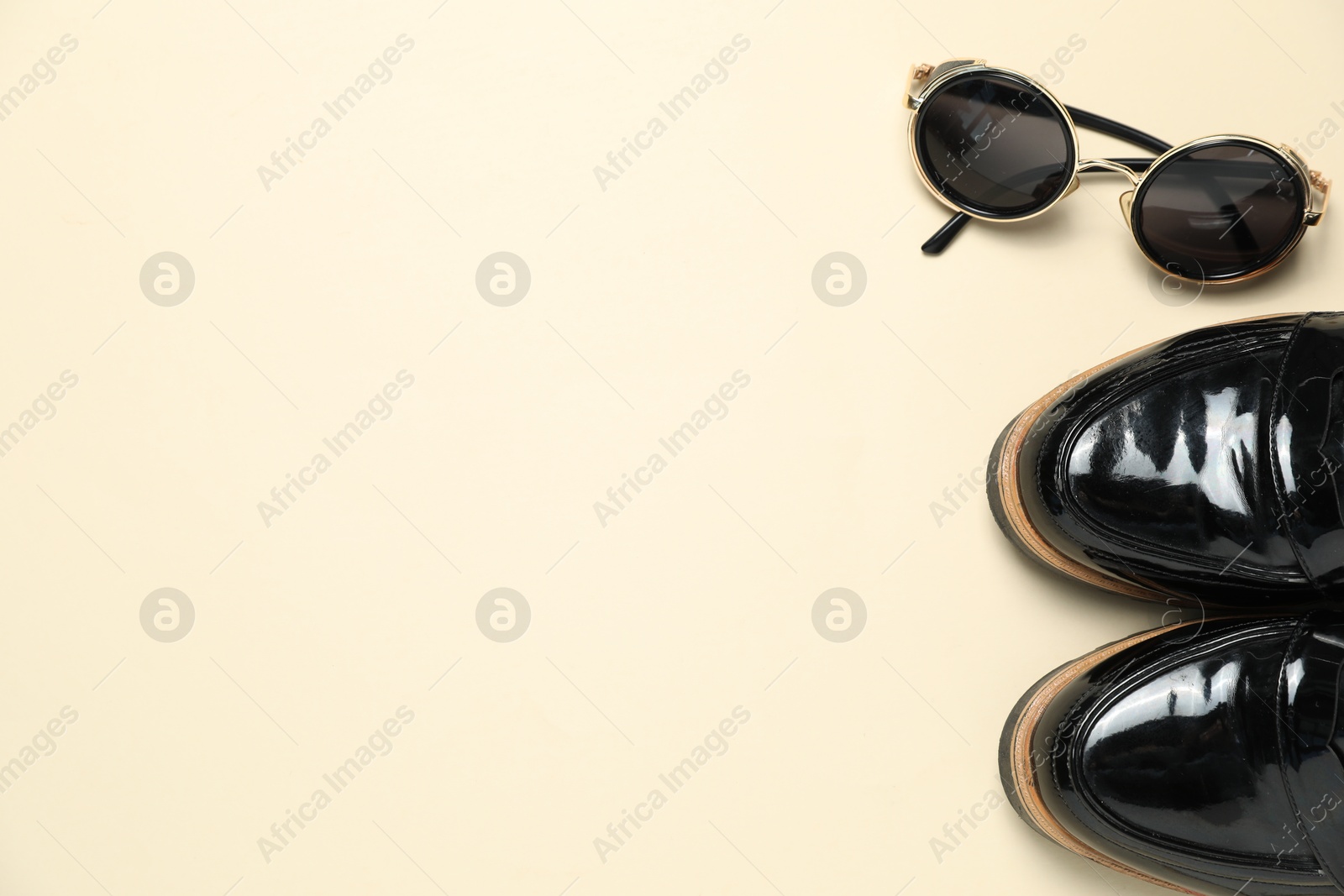 Photo of Stylish shoes and sunglasses on beige background, flat lay. Space for text