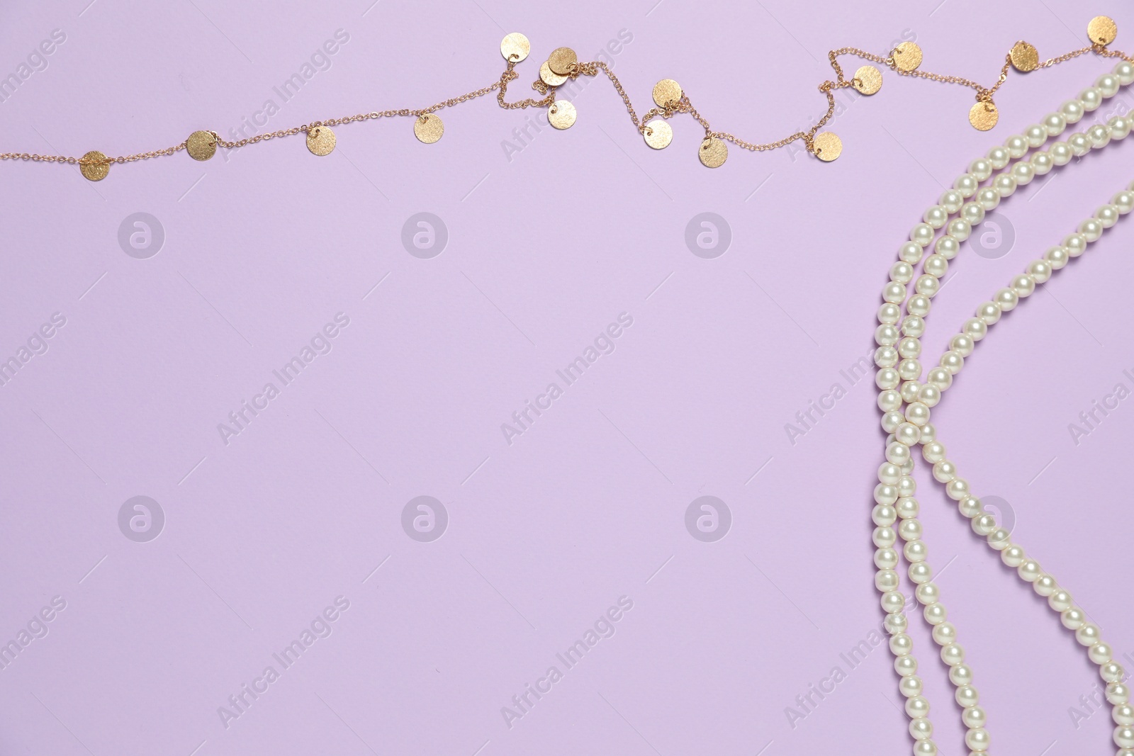 Photo of Beautiful pearl and golden necklaces on violet background, flat lay. Space for text