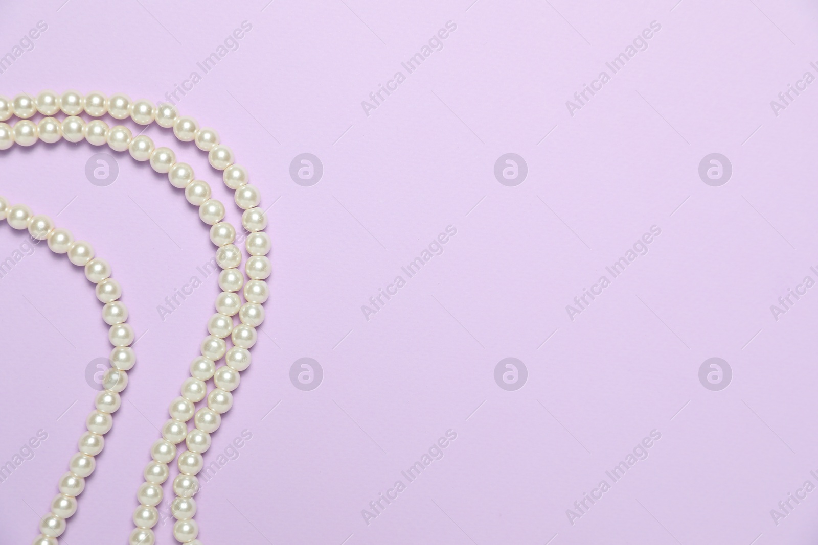 Photo of Beautiful pearl necklaces on violet background, flat lay. Space for text