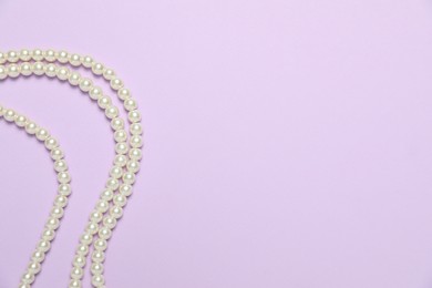 Photo of Beautiful pearl necklaces on violet background, flat lay. Space for text