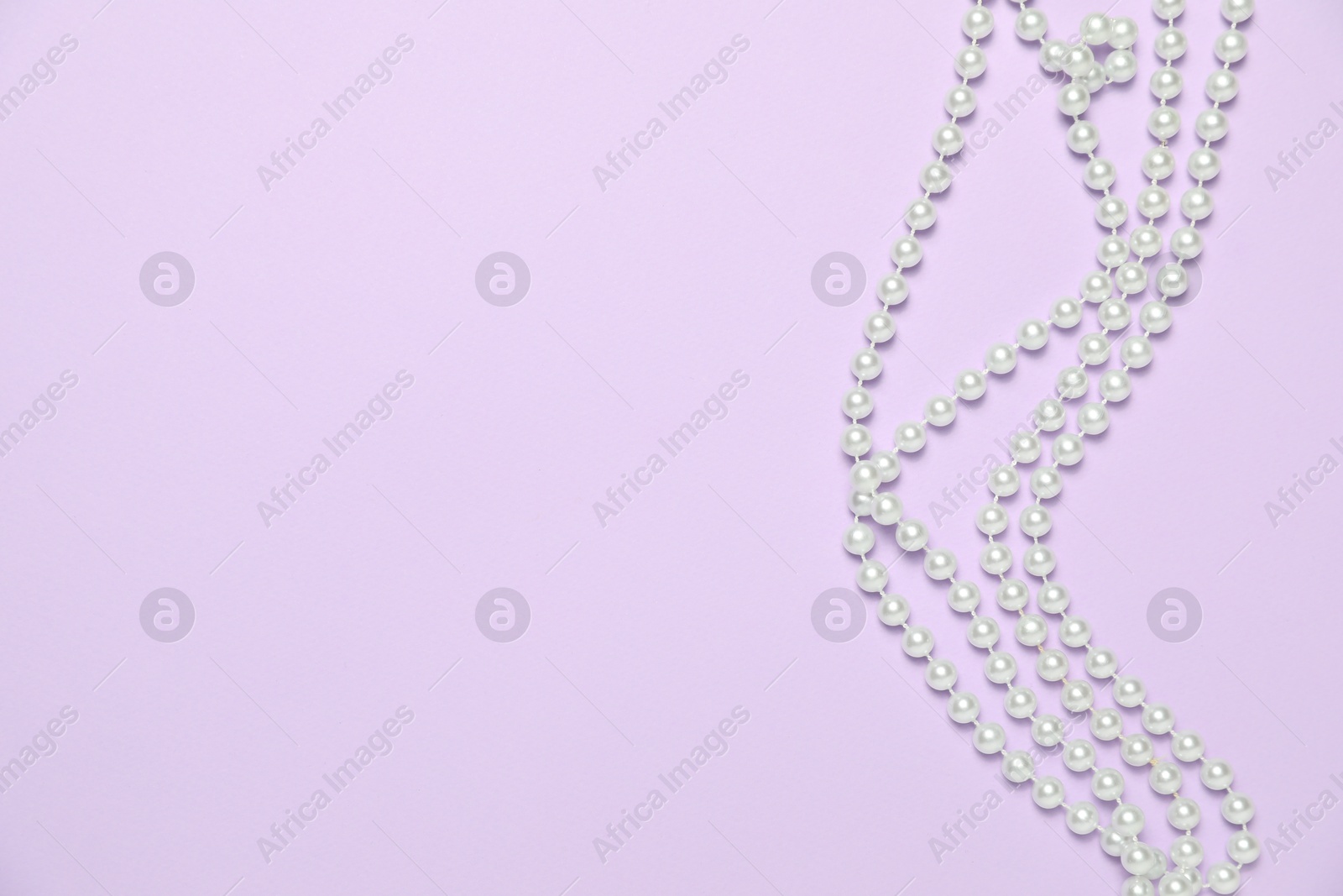 Photo of Beautiful pearl necklaces on violet background, flat lay. Space for text