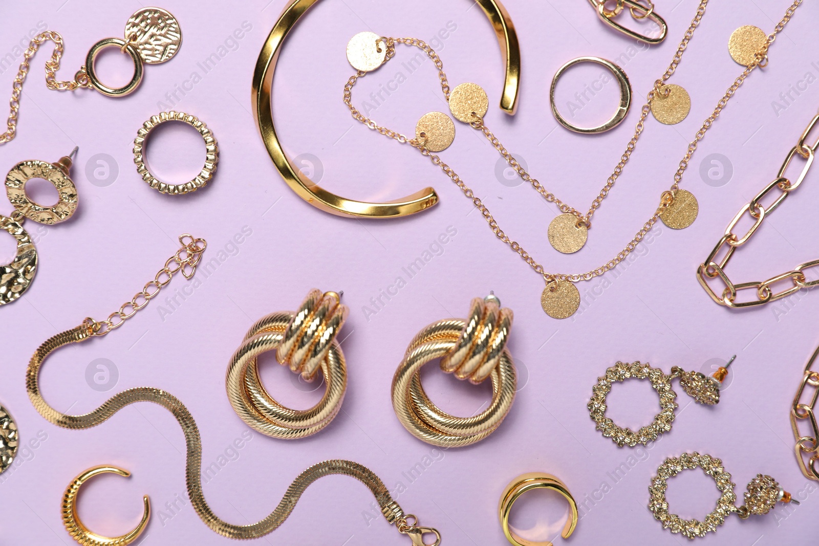 Photo of Flat lay composition with golden jewelry on violet background