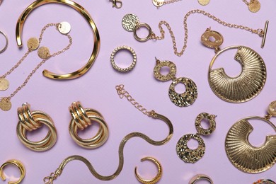 Photo of Flat lay composition with golden jewelry on violet background