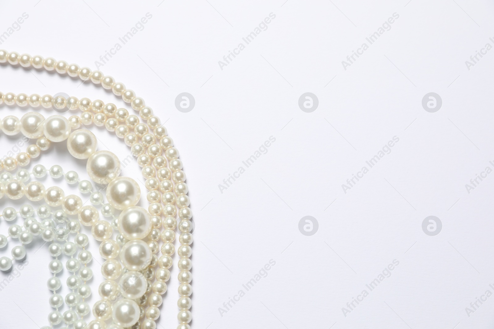 Photo of Beautiful pearl necklaces on white background, flat lay. Space for text