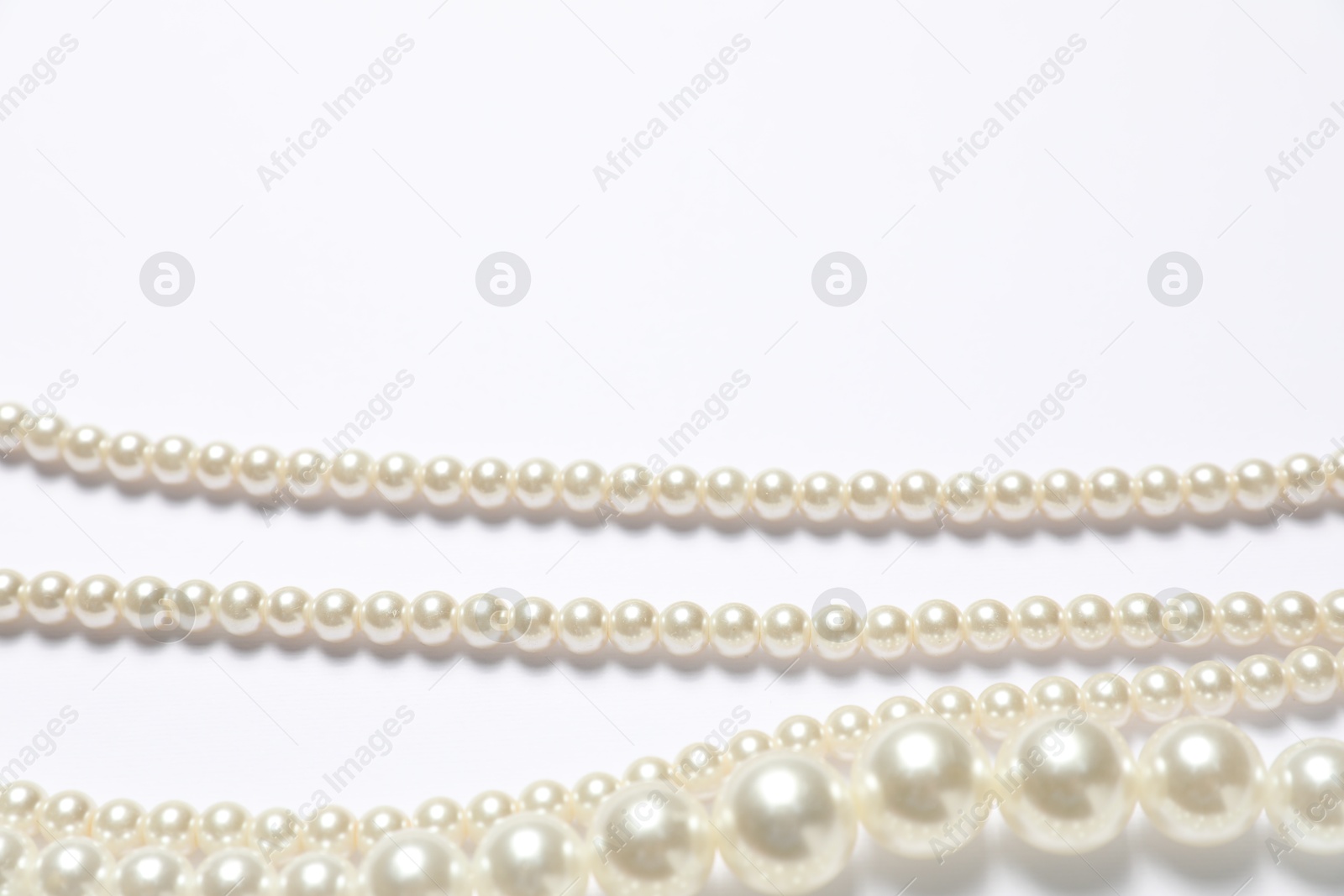 Photo of Beautiful pearl necklaces on white background, flat lay. Space for text