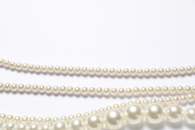 Photo of Beautiful pearl necklaces on white background, flat lay. Space for text