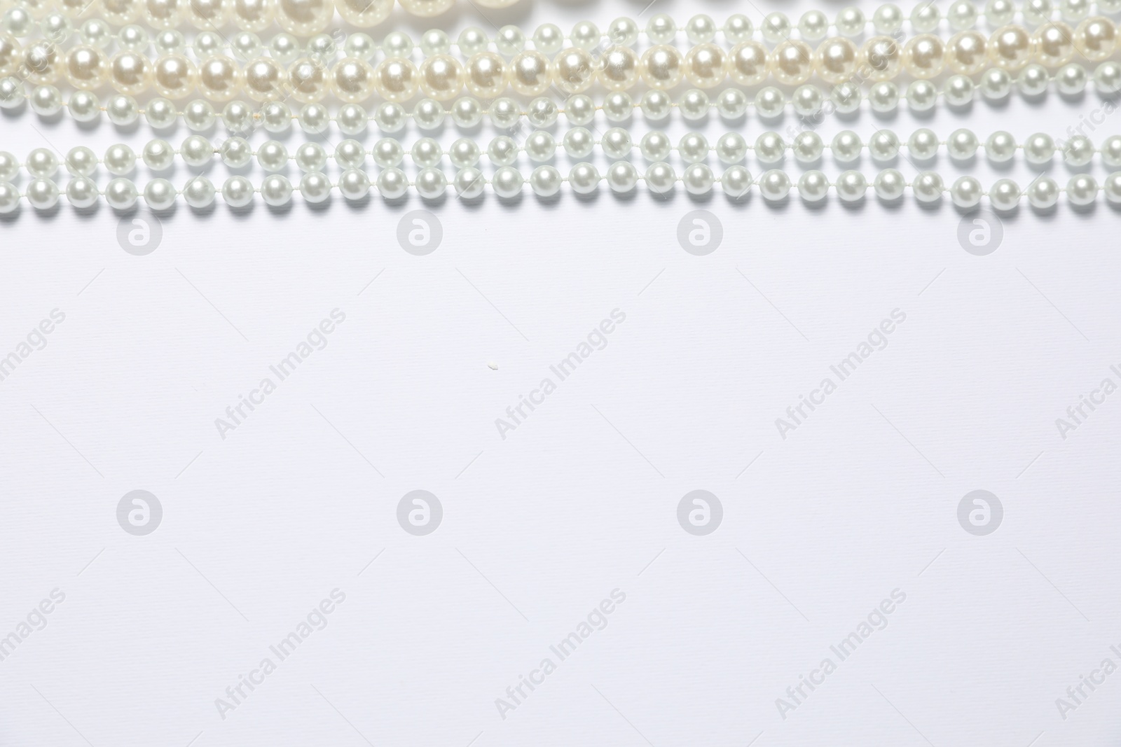 Photo of Beautiful pearl necklaces on white background, flat lay. Space for text