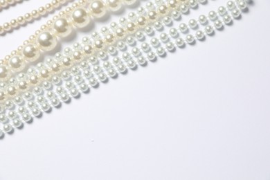 Photo of Beautiful pearl necklaces on white background, flat lay. Space for text