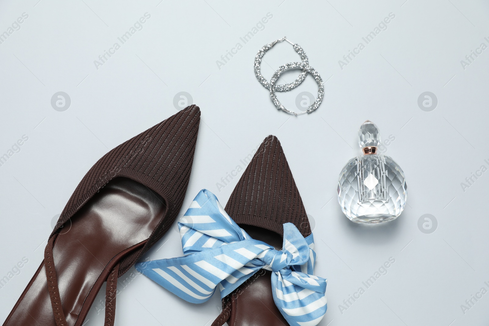 Photo of Stylish shoes, bottle of perfume and earrings on light grey background, flat lay