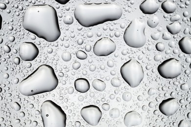 Photo of Water drops on light glass surface, top view