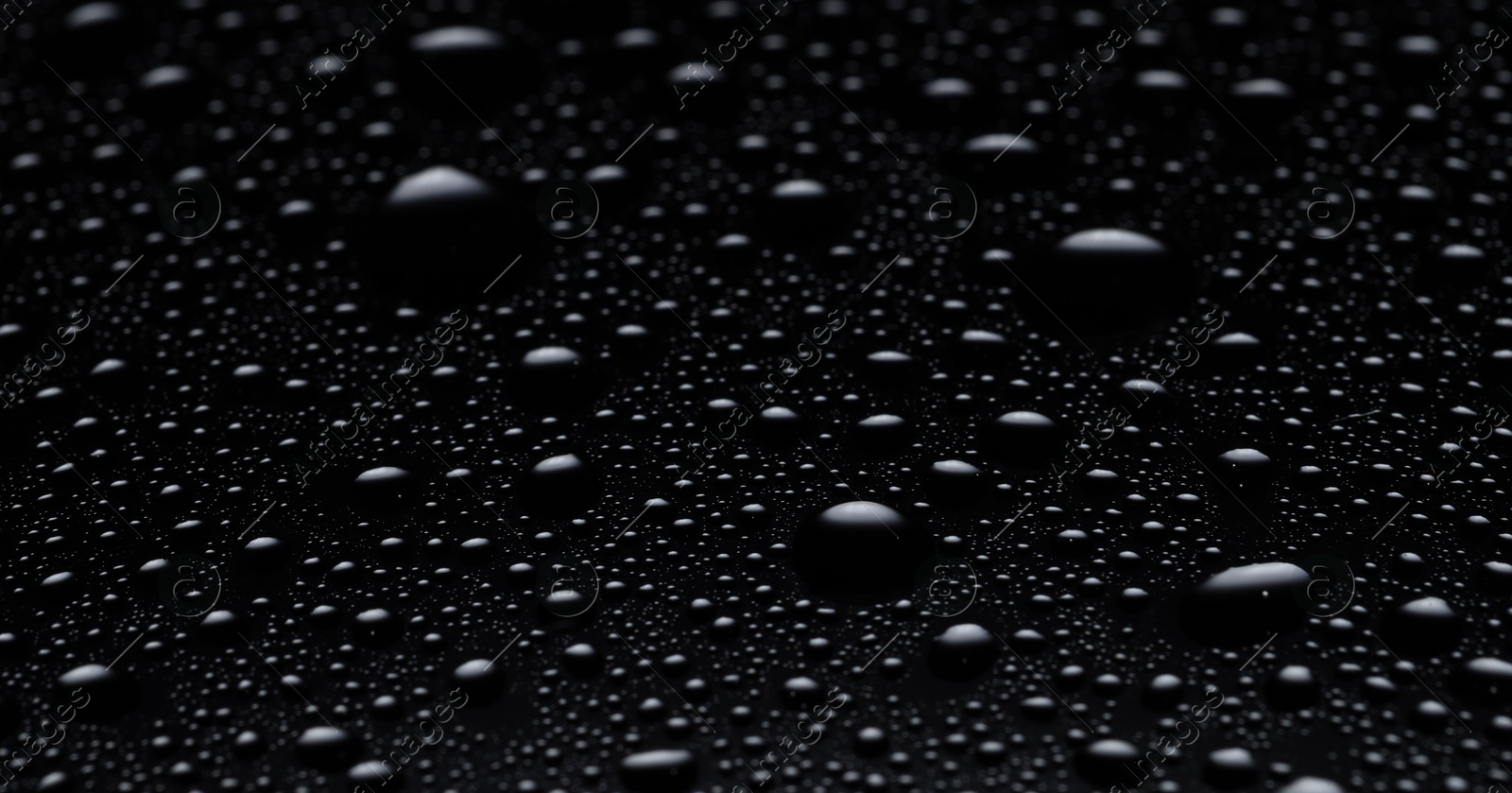 Photo of Water drops on black glass surface, closeup