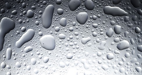 Photo of Water drops on grey glass surface, top view