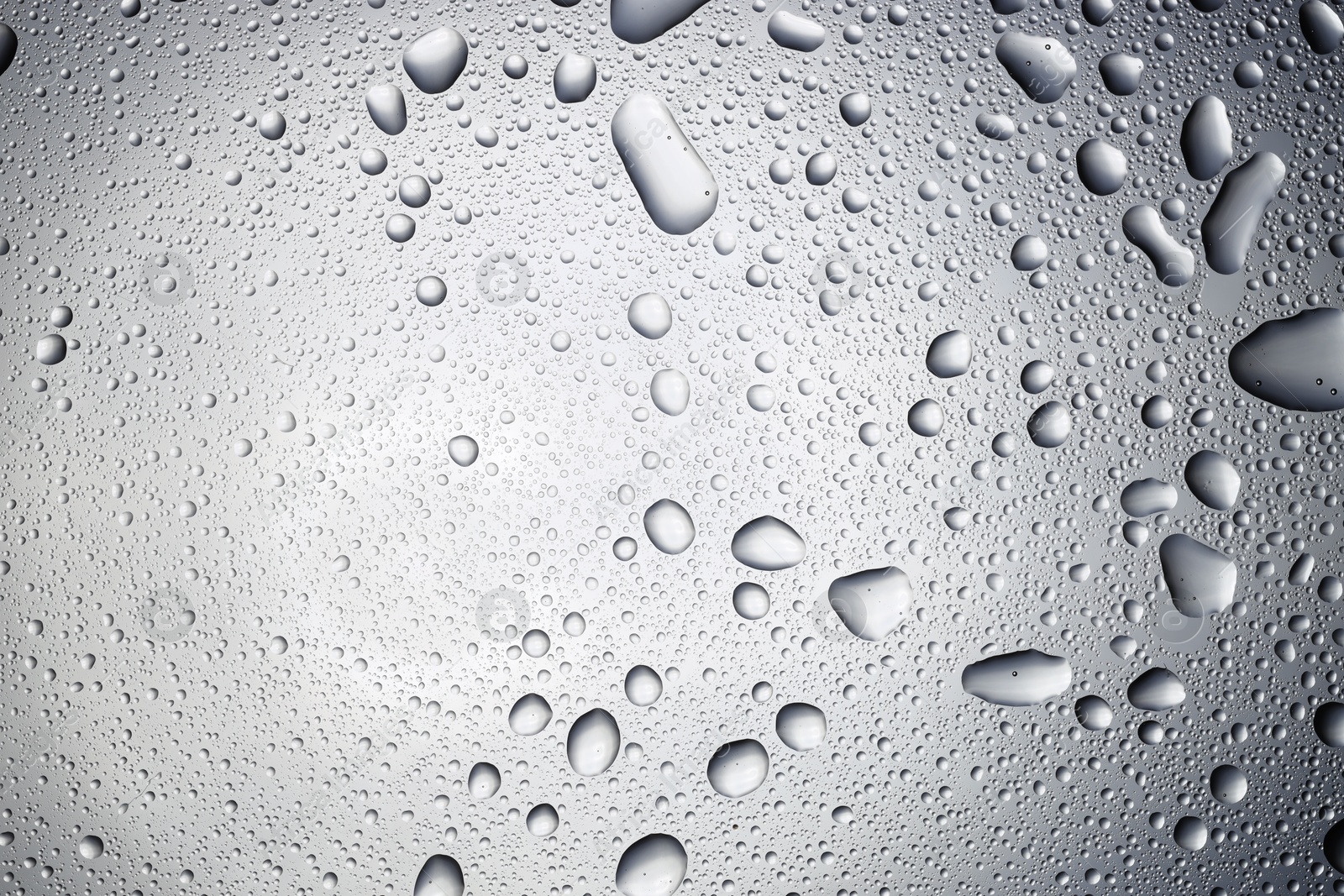 Photo of Water drops on light glass surface, top view