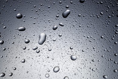 Photo of Water drops on grey glass surface, top view