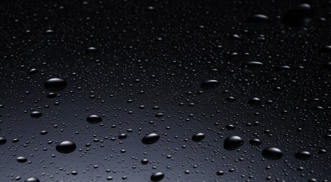 Photo of Water drops on dark glass surface, closeup